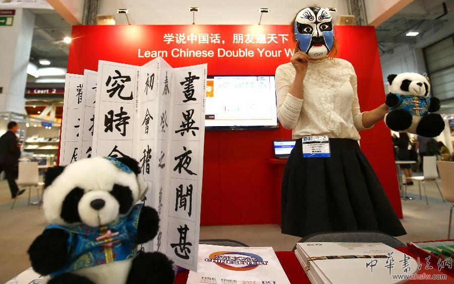 4月8日，在英国伦敦书展上，一位工作人员在中国国家汉办的展台戴面具介绍产品。