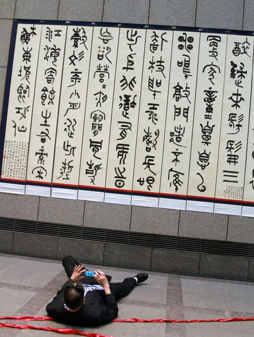 一名观众仰躺在地，力图拍下书法作品的全景。人民网特派记者管克江摄